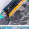 A close-up view of a black and yellow 2-in-1 floor scrub brush with bristles and a squeegee being used on a dark, wet floor s