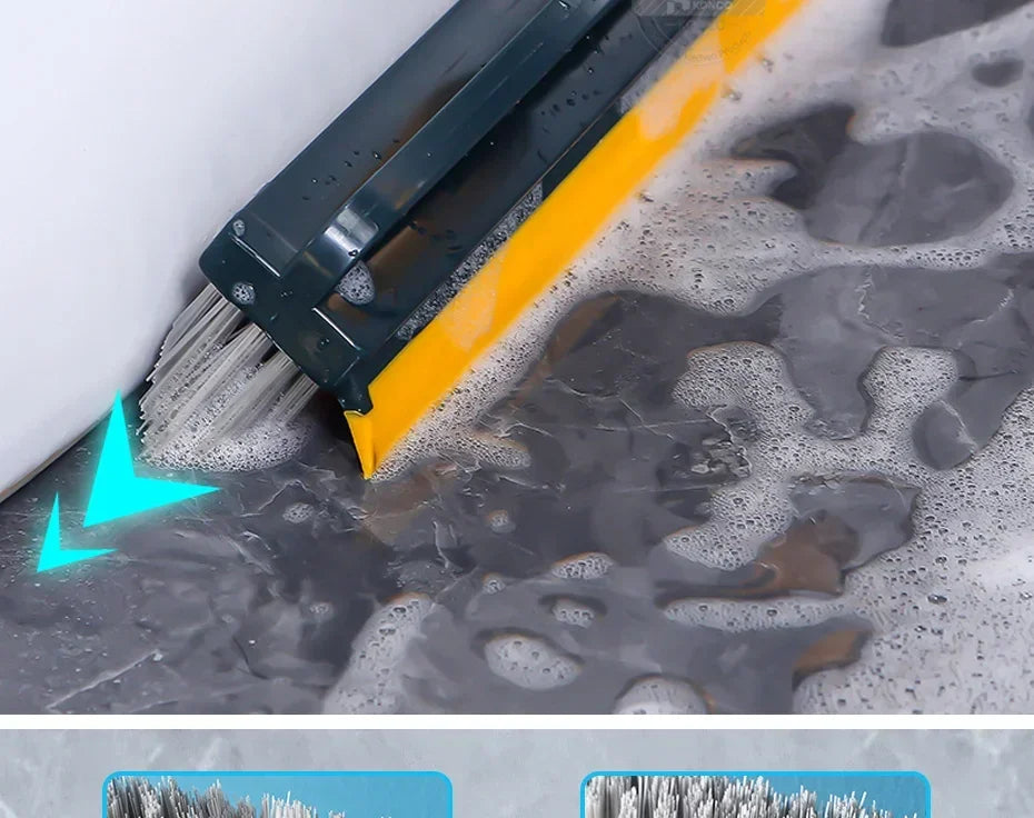 A close-up view of a black and yellow 2-in-1 floor scrub brush with bristles and a squeegee being used on a dark, wet floor s