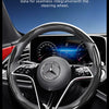 A close-up view of a black steering wheel with a carbon fiber texture cover installed in a Mercedes-Benz interior.