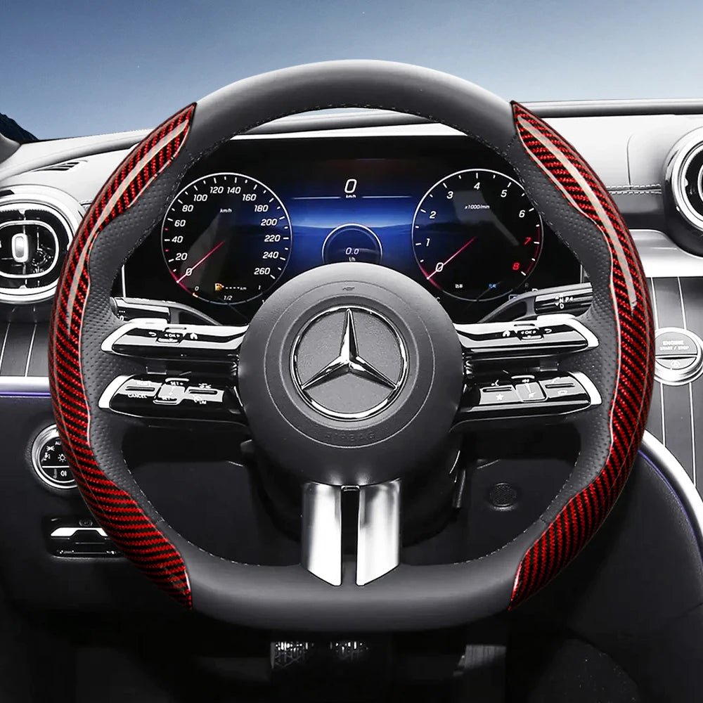 Close-up view of a black steering wheel with red carbon fiber texture accents and Mercedes-Benz instrument cluster.