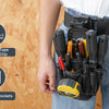 A person is wearing a black heavy-duty tool pouch with a belt clip attached to their jeans, highlighting its features.