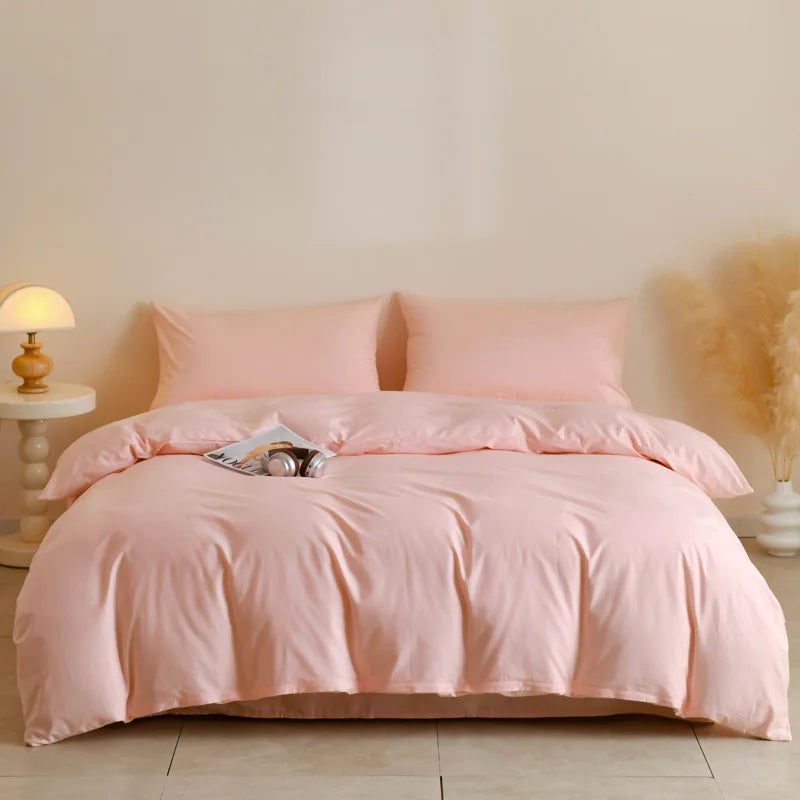 A pink quilted duvet cover set with matching pillowcases displayed on a bed.