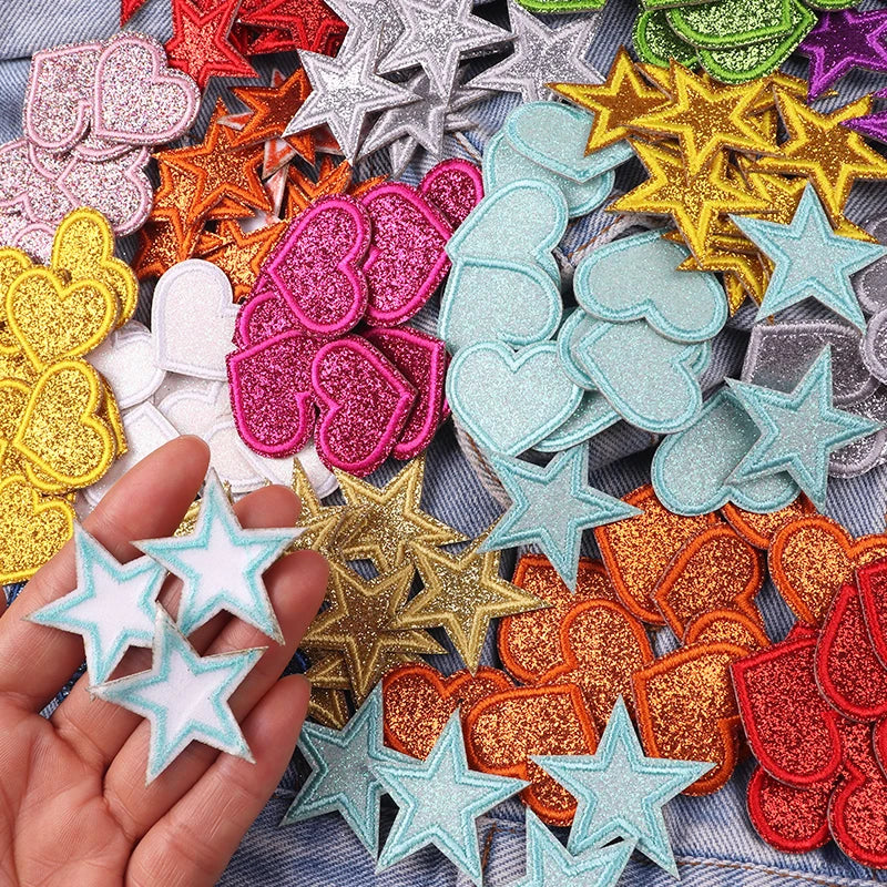A collection of colorful glitter heart and star iron-on embroidered patches in various shades and shapes.