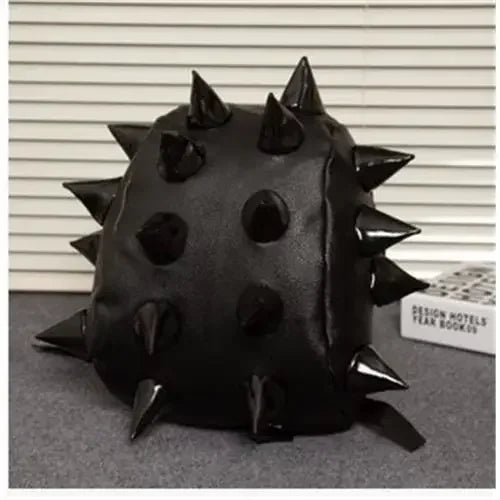 A black, spiky PU leather backpack with rivets resting on a gray surface.
