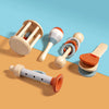 A collection of wooden baby rattles and bells in natural wood tones and orange accents on a beige background.