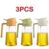 Three amber glass oil spray bottles with white and green tops for cooking.