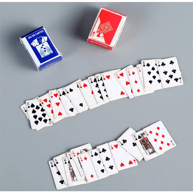 A collection of mini playing cards featuring various suits and face cards, displayed on a gray surface.
