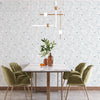A dining room features a white marble table and green upholstered chairs against a light patterned wallpaper.