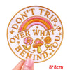 Pink and gold embroidered patch with the text Don't Trip Over What You Behind You