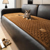A tabby cat sits on a brown quilted plush sofa cover with non-slip backing.