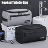 A gray and black hooked toiletry bag is shown next to a black light travel toiletry bag and a silver faucet.