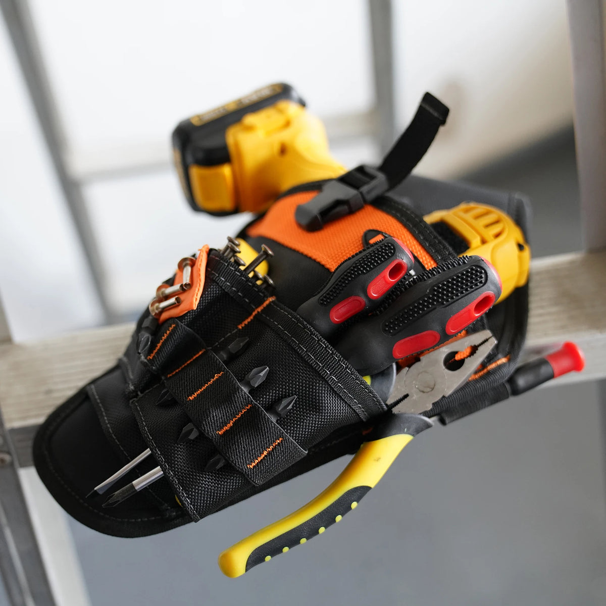 A black heavy duty drill holster waist tool bag with an orange and yellow magnetic screw holder is shown in a close-up view.