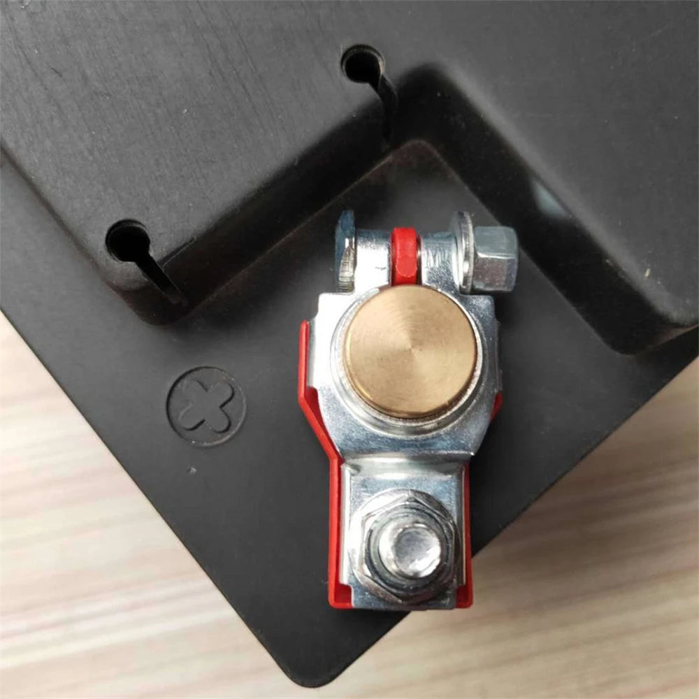 A close-up view of two quick-release copper car battery terminals with red and silver components mounted on a black panel.
