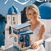 A woman holds a small wooden beach corner DIY book nook kit with blue accents and LED lighting on a stone surface.