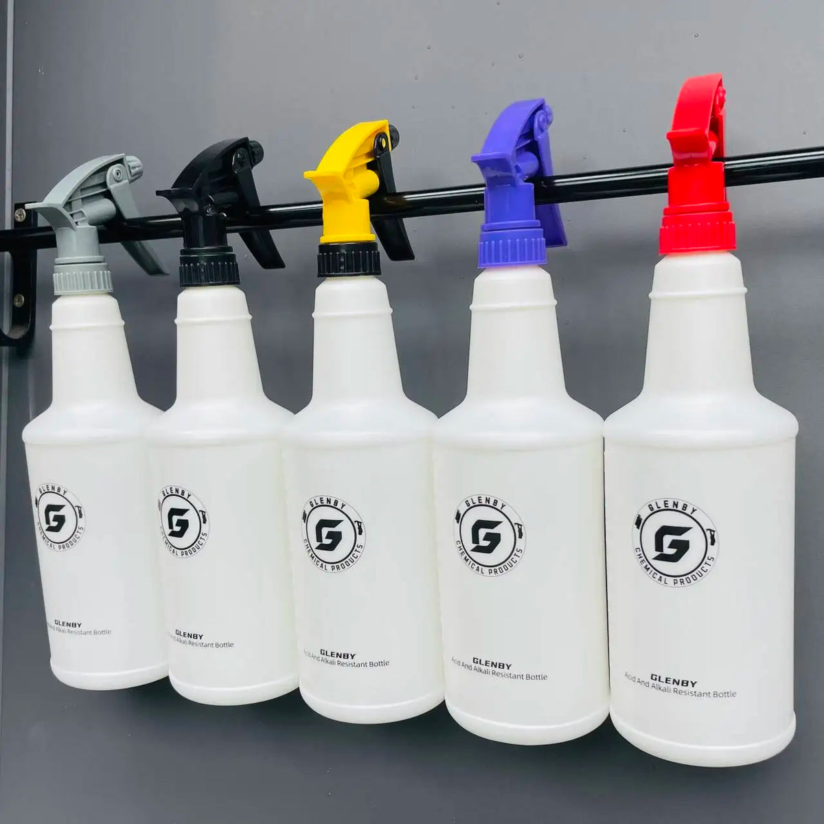 A row of white plastic spray bottles with black pump tops lined up on a dark surface.
