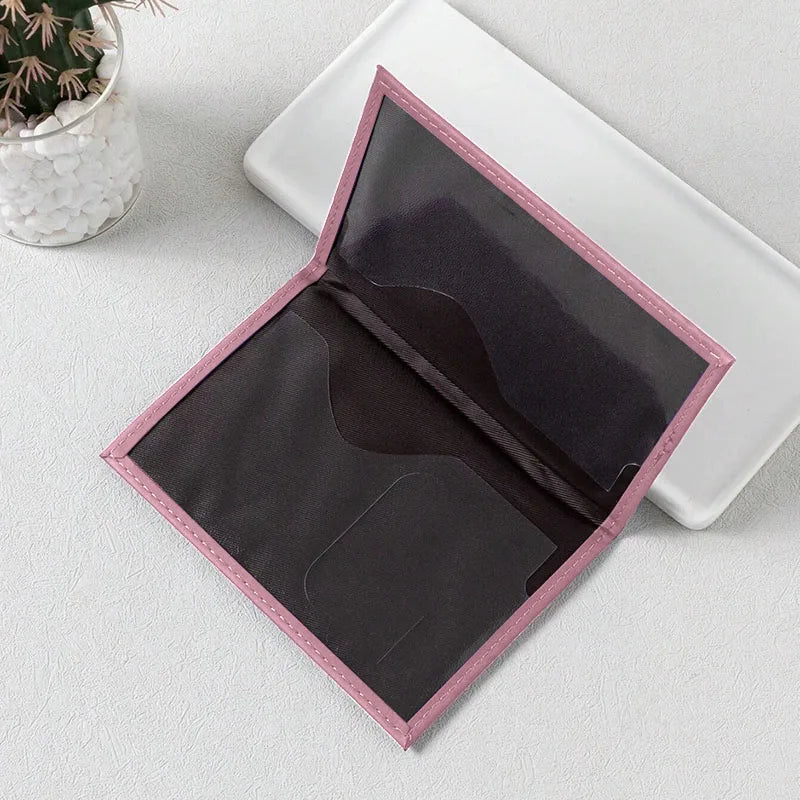 A pink-edged black PU leather passport holder with card slots is shown open on a white surface.