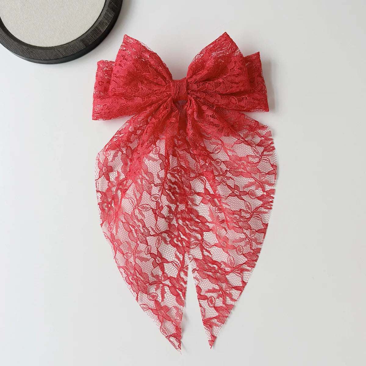 A vibrant red lace bow accessory for hair, featuring intricate floral patterns and a sheer fabric.