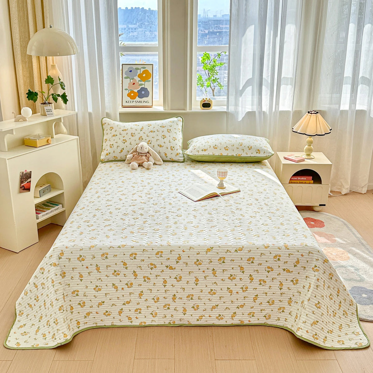 A floral quilted bedspread with a dust-proof cover is displayed on a bed in a bright room.