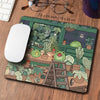 A large extended mousepad featuring a kawaii nature design of frogs and plants on a wooden desk.