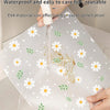 A white reusable mat with daisy flowers is being washed under running water.