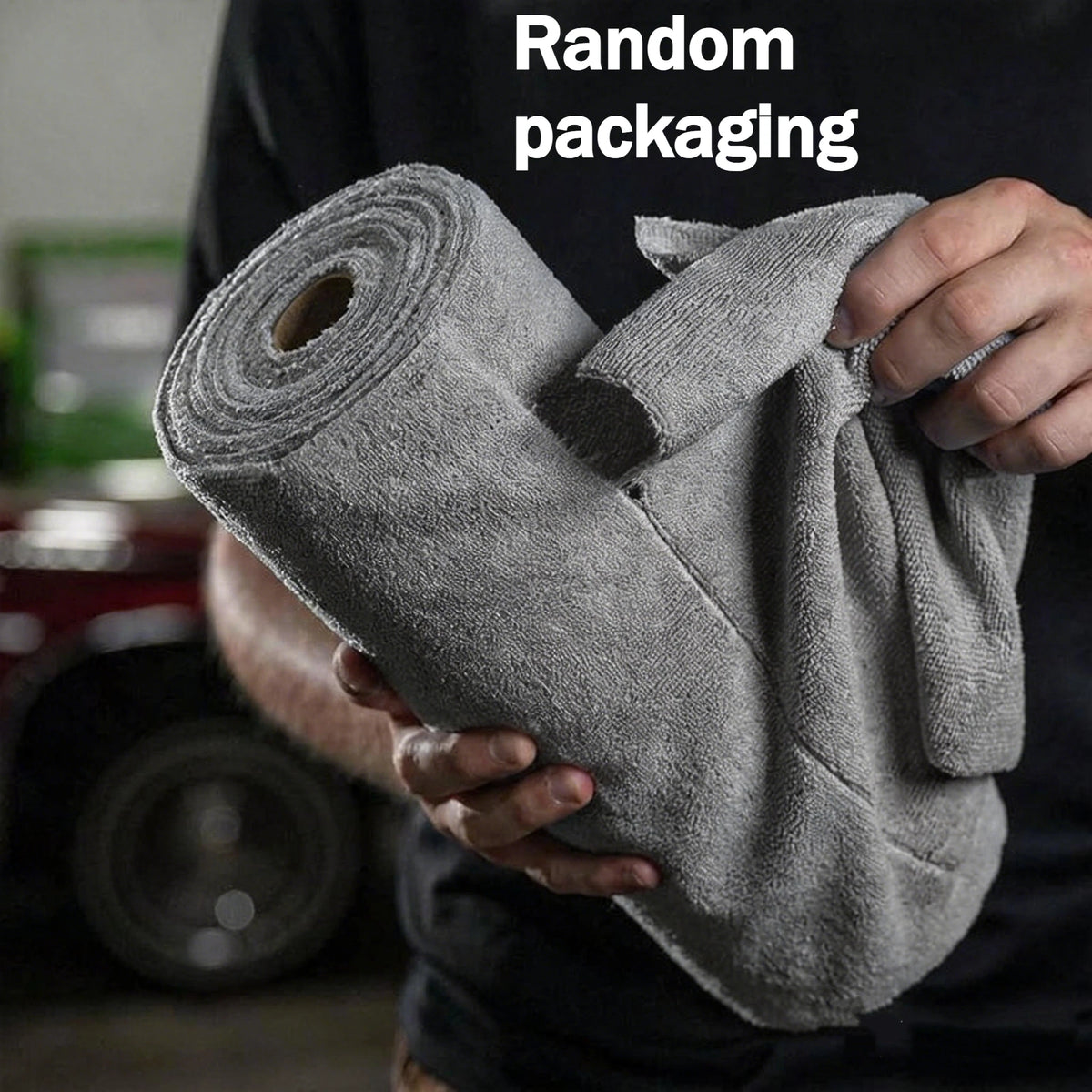 A hand holds a roll of gray microfiber cleaning cloths, demonstrating random packaging.