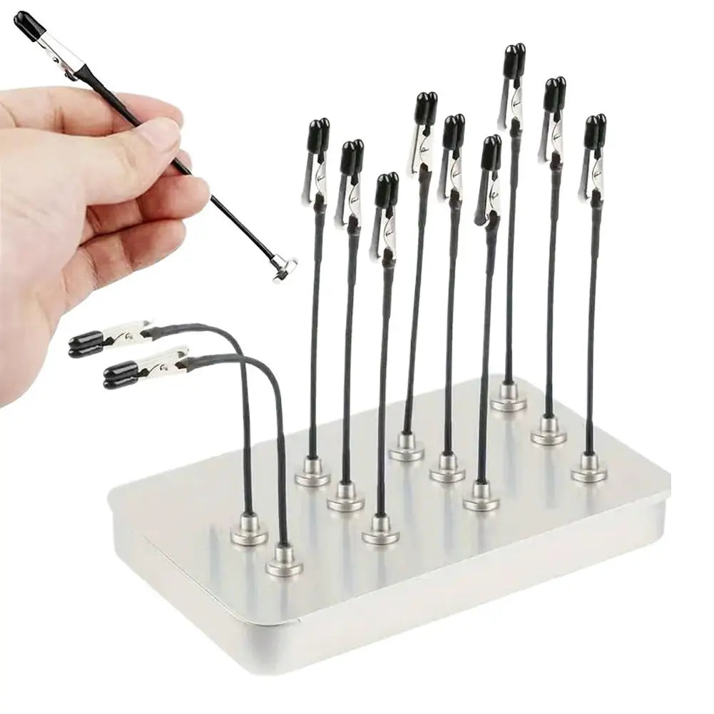 A hand holds a magnetic helping hands tool with a flexible gooseneck arm and alligator clip attached to several metal rods.