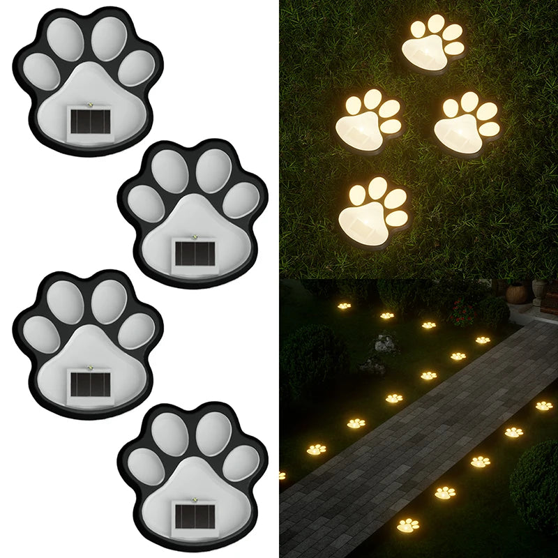 A set of four solar dog paw pathway lights illuminating a stone walkway in a garden.