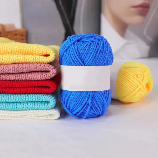A collection of brightly colored blue, yellow, and pink knitting yarn skeins displayed on a white surface.