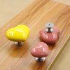 A set of heart-shaped toilet flush buttons in yellow and pink resting on a wooden surface.