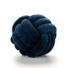 A dark navy blue, hand-knotted velvet throw pillow with a round, textured surface.