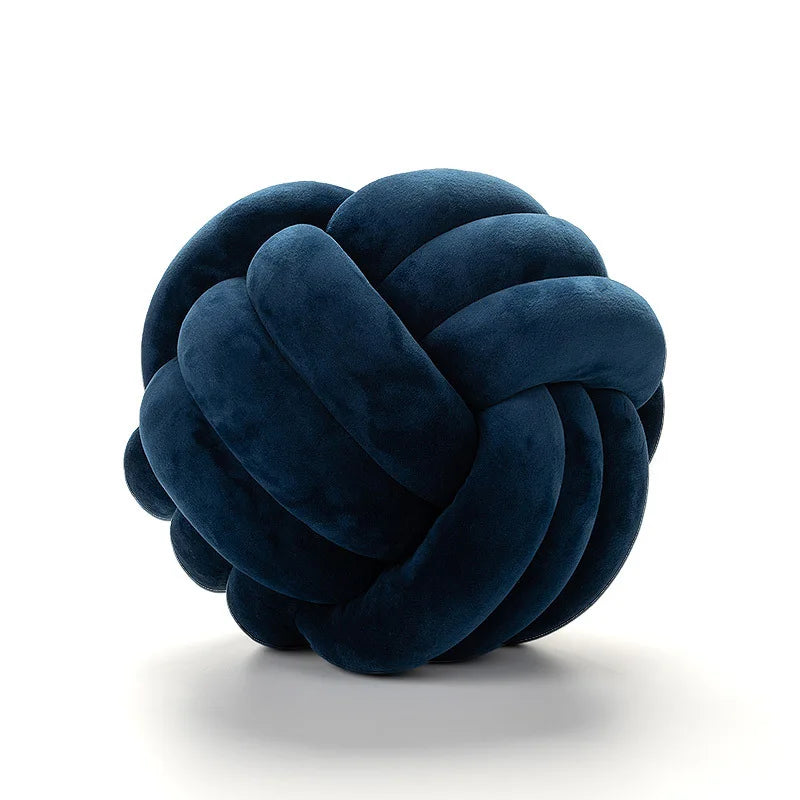 A dark navy blue, hand-knotted velvet throw pillow with a round, textured surface.
