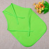 A bright lime green non-woven fabric craft apron folded and displayed on a beige cloth with orange flowers.
