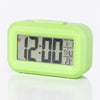 A lime green compact LED digital alarm clock with a display showing 12:00 and various time/date information.
