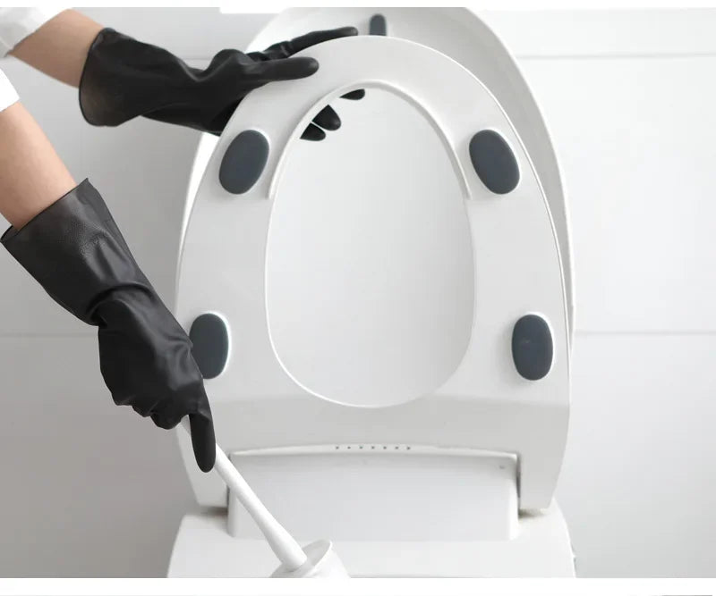 A hand wearing a black rubber cleaning glove is operating a white, circular cleaning device.
