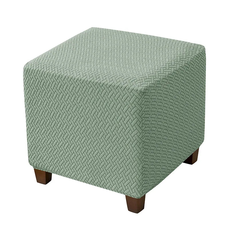 A square ottoman slipcover in a muted sage green color with a diamond lattice pattern.