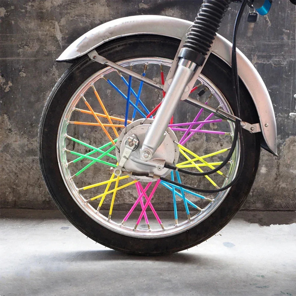 A close-up of a motorcycle wheel with a silver rim and colorful spoke covers.