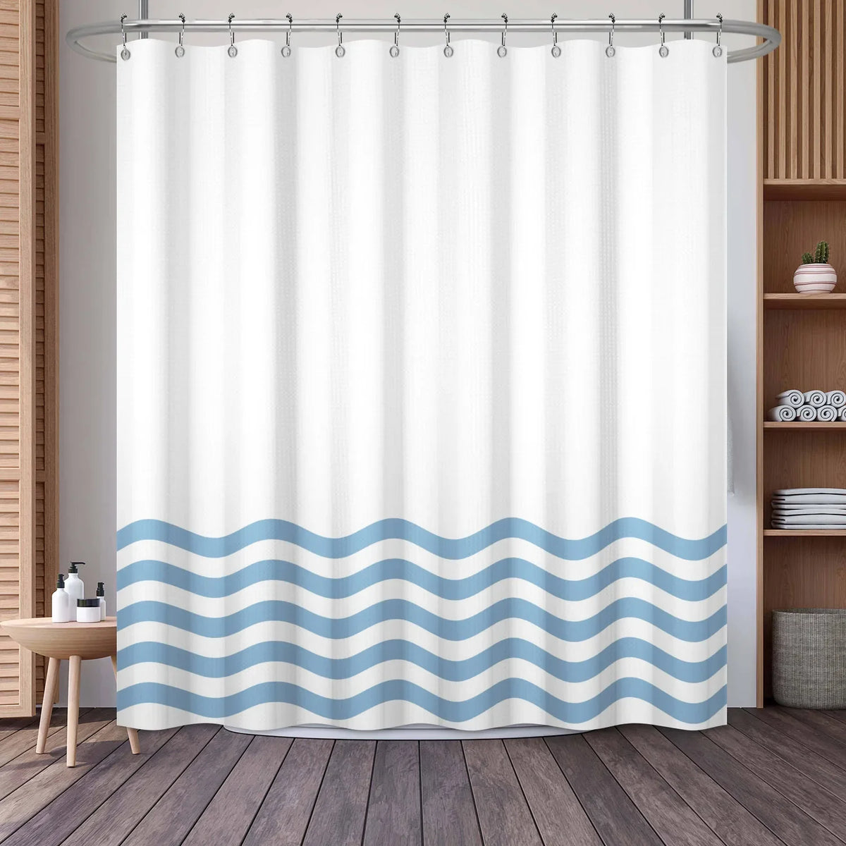 White shower curtain featuring a blue wavy stripe pattern hanging from a metal rod.