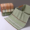 A stack of soft, textured bath towels in shades of beige, green, and orange, with one towel displayed prominently.
