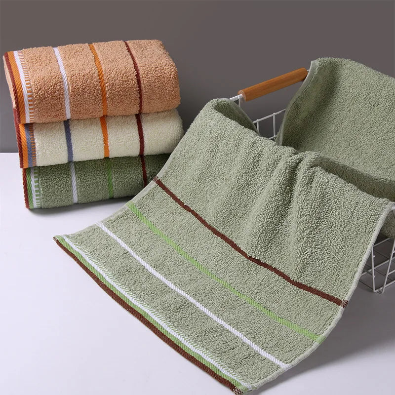 A stack of soft, textured bath towels in shades of beige, green, and orange, with one towel displayed prominently.