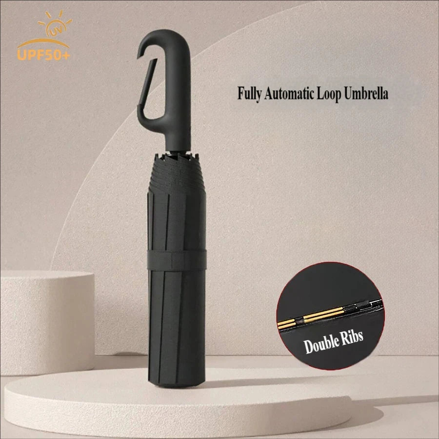 A black fully automatic loop umbrella standing upright on a light surface.
