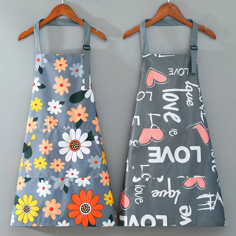 A gray apron with a floral print featuring pink and orange hearts and leaves, hanging on a wooden hanger.