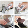 Hands are using an Emery Cleaning Sponge to scrub stubborn stains on a faucet and a pot.