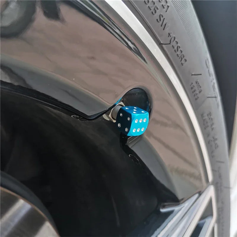 A close-up view of a tire valve stem with an aluminum alloy dice design cap installed.