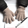 A pair of light brown, fuzzy plush winter gloves resting on a piece of lined paper with red lines.