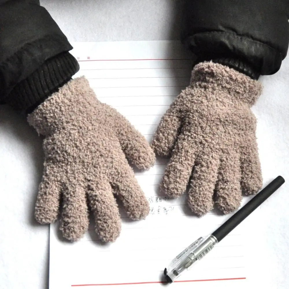 A pair of light brown, fuzzy plush winter gloves resting on a piece of lined paper with red lines.