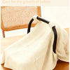 A beige breathable cotton muslin car seat and stroller cover draped on a wooden surface.