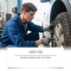 A man in a blue shirt is applying a rust remover spray to a car tire with a gloved hand.