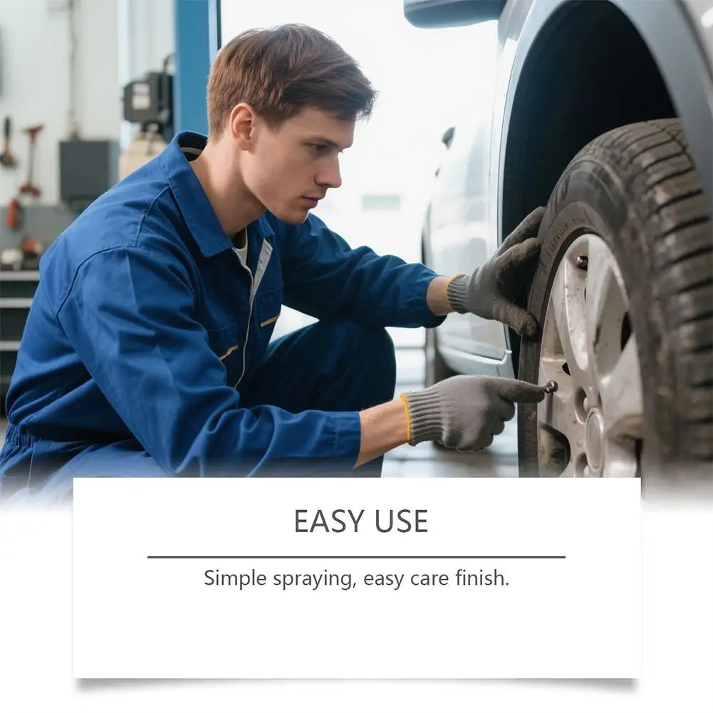 A man in a blue shirt is applying a rust remover spray to a car tire with a gloved hand.