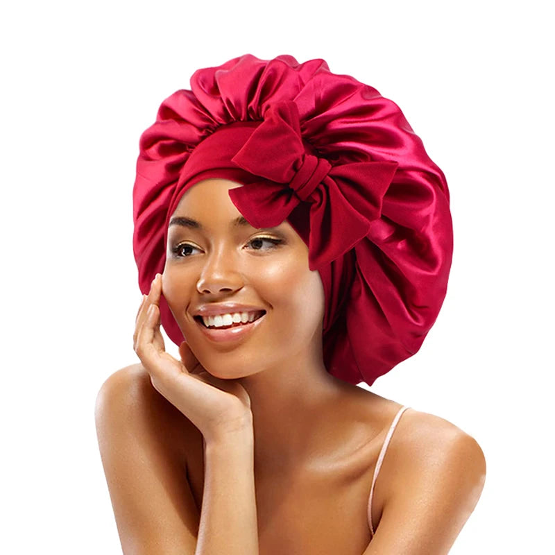 A woman wearing a vibrant red satin sleeping bonnet with an adjustable tie.
