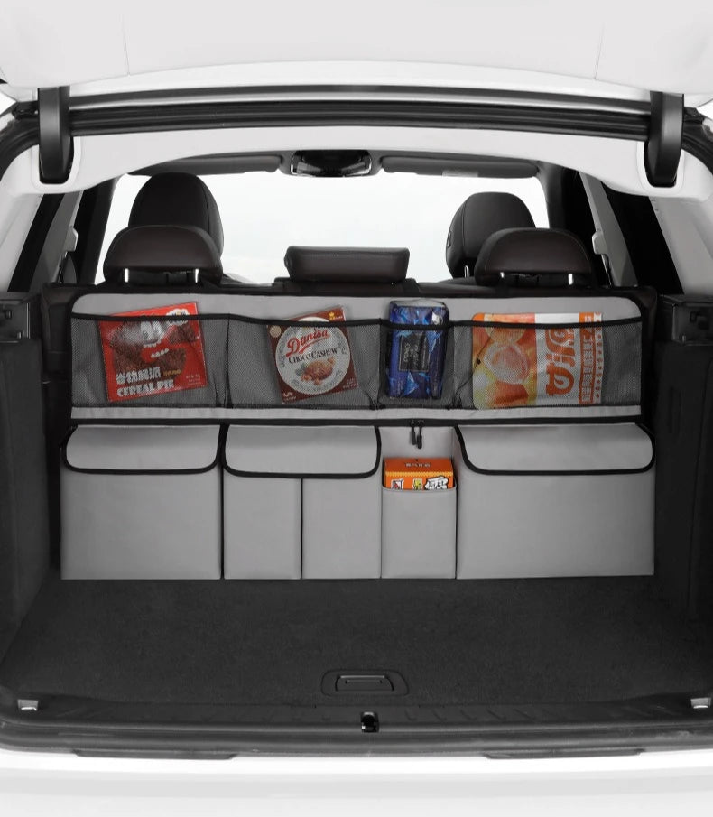 Interior view of a car showing a foldable trunk organizer with seat back storage and various items in the compartments.